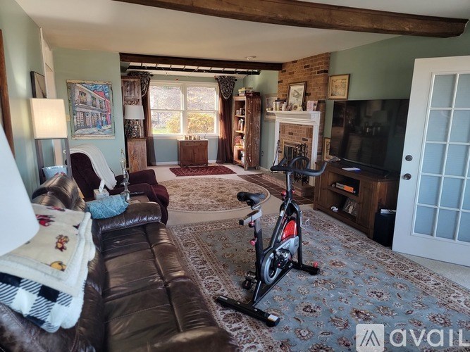 A living room with a brown leather couch and a bicycle on the carpet.