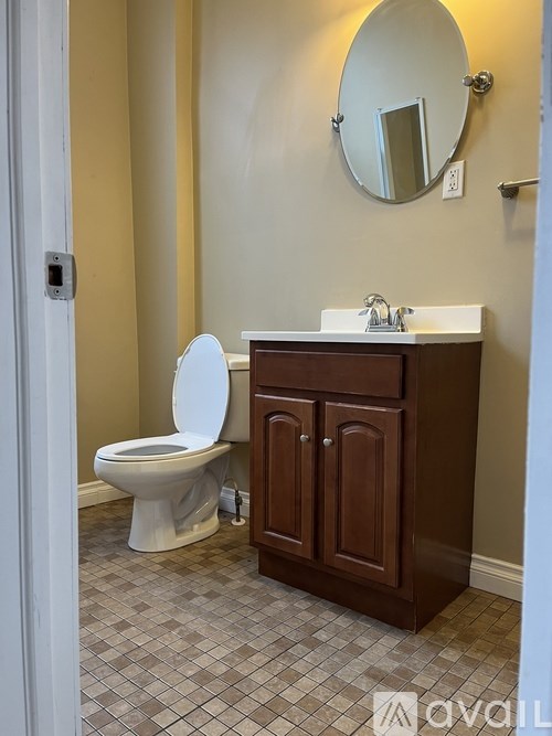 A bathroom with a toilet, sink and mirror.
