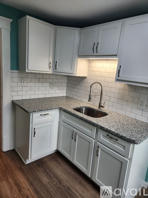 A kitchen with white cabinets and a granite countertop.