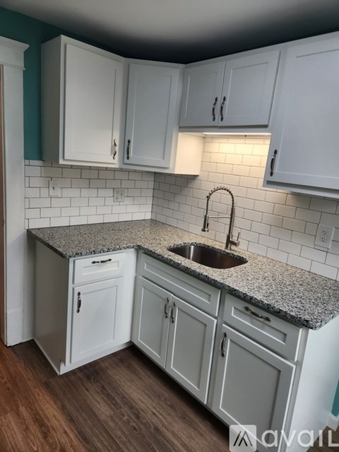 A kitchen with white cabinets and a granite countertop.