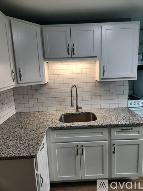 A kitchen with granite countertops and white cabinets.