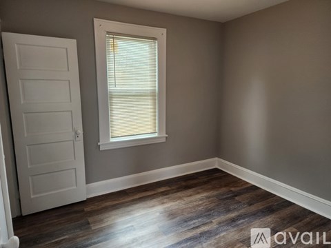 A room with a white door and a window with blinds.