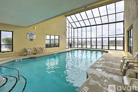 A pool with a glass ceiling and chairs around it.