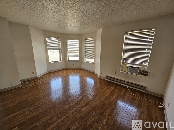A room with wooden floors and three windows.