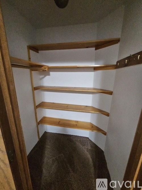 A wooden shelving unit with four shelves is mounted on a white wall.