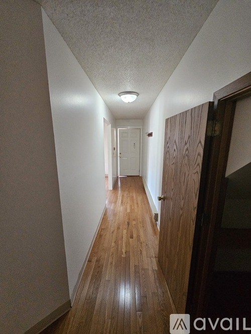 A long hallway with wooden floors and white walls.