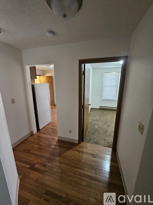 A hallway with a wooden floor and a door leading to a bedroom.