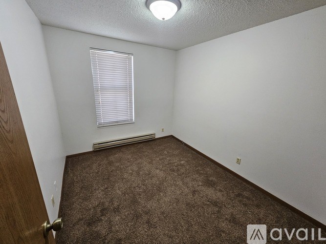 A room with a carpeted floor and a window with blinds.