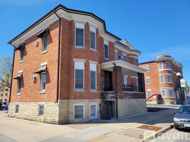 A red brick building with a stone foundation and a balcony on the second floor.