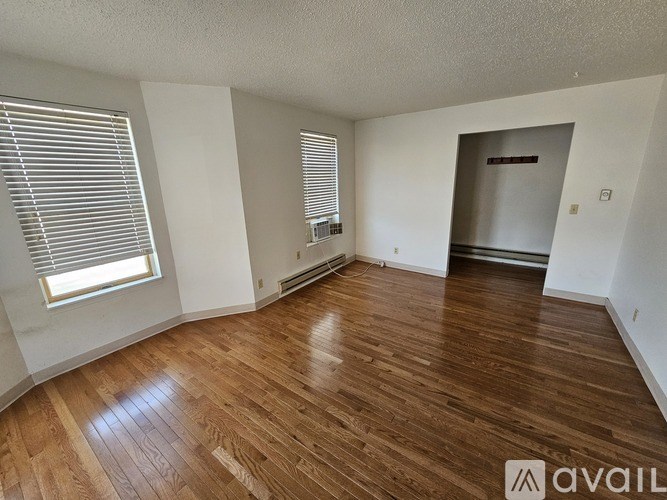 A room with wooden flooring and a window with blinds.