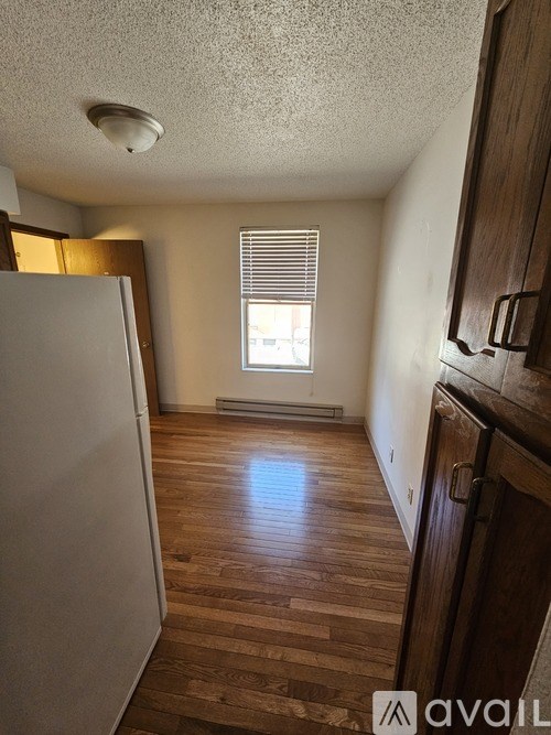 A kitchen with wooden floors and a white refrigerator.
