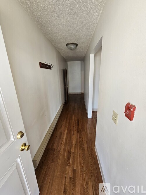 A hallway with wood floors and white walls.