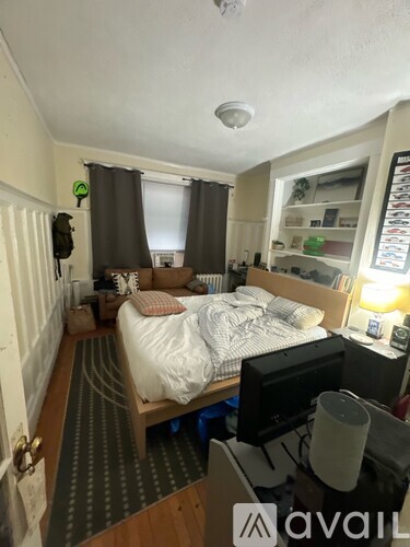 A bedroom with a bed, desk, and a window with curtains.