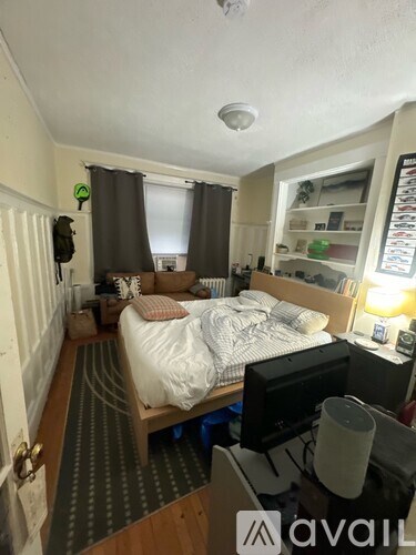 A bedroom with a bed, desk, and a window with curtains.