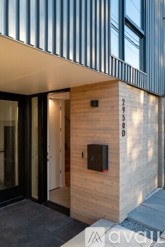 A modern house entrance with a wooden wall and a black door.