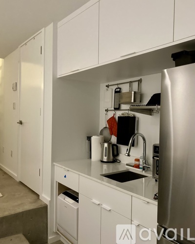 A kitchen with white cabinets and a stainless steel refrigerator.