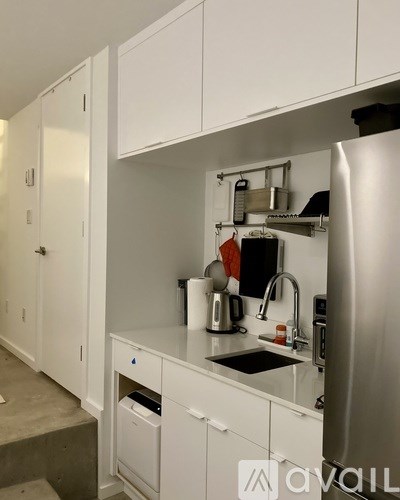 A kitchen with white cabinets and a stainless steel refrigerator.
