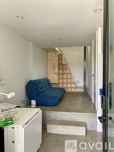 A blue chair is in the corner of a room with a staircase.