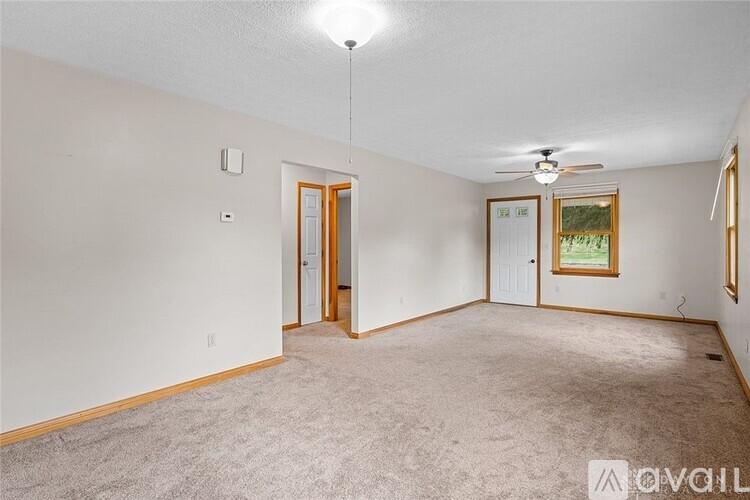 A spacious room with a carpeted floor and a ceiling fan.