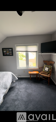 A bedroom with a bed, a chair, and a window.