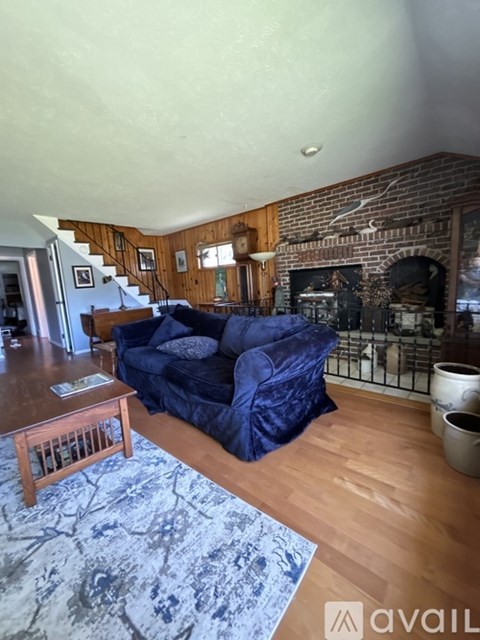 A living room with a blue couch and a fireplace.