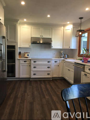 A kitchen with white cabinets and a wooden floor.