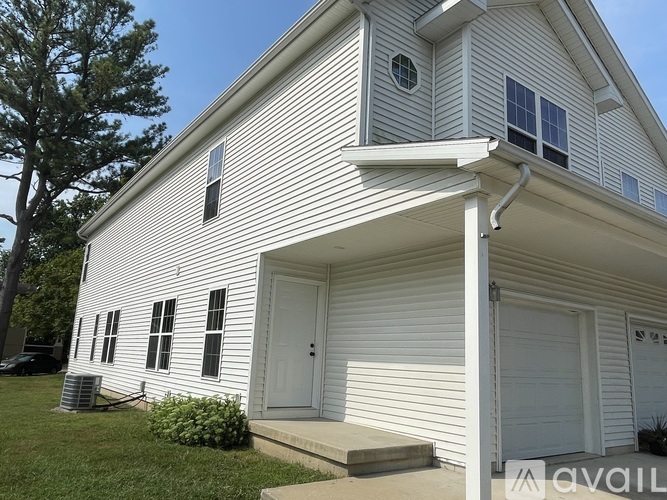 A white house with a garage door and a window on the side.