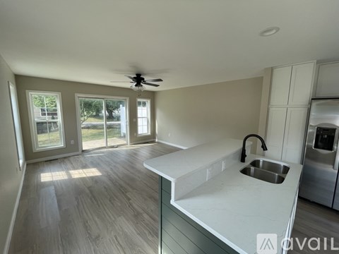 A kitchen with a fan on the ceiling and a sink with a faucet.