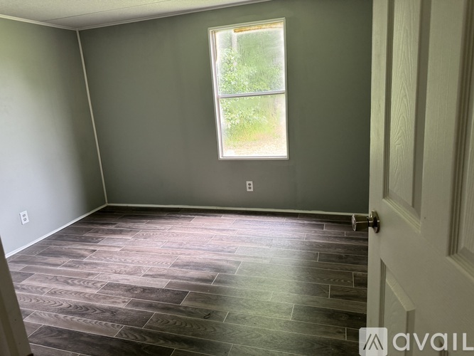 A room with a window and a wooden floor.