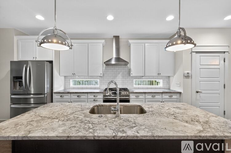 A kitchen with a marble countertop and stainless steel appliances.