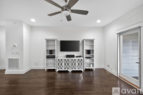 A spacious living room with a television and entertainment center.