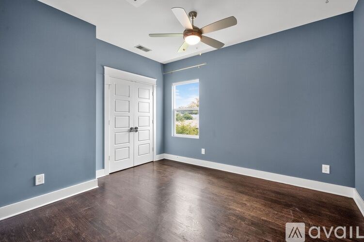 A room with a ceiling fan and a door leading to a balcony.