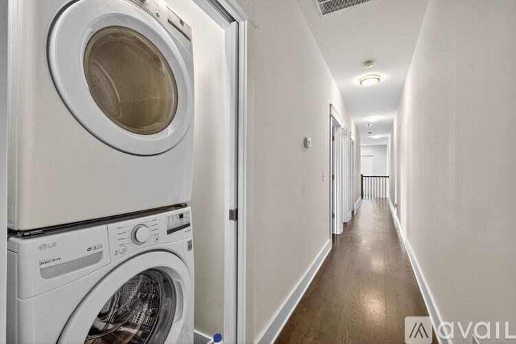 A white washing machine is in a narrow hallway.