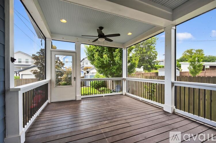 A wooden deck with a ceiling fan and a view of the backyard.