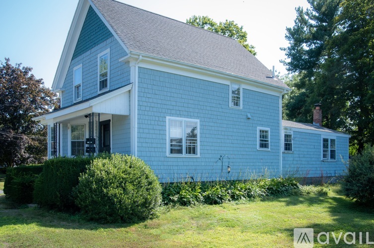 A blue house with a white trim and a large front porch.