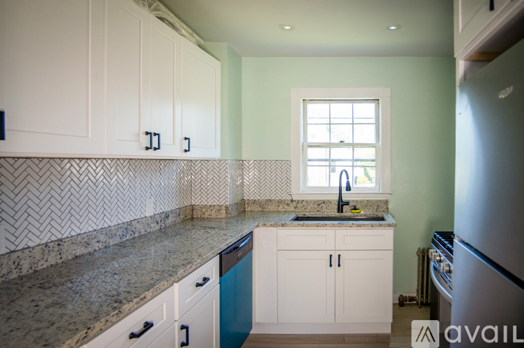 A kitchen with white cabinets and a marble countertop.