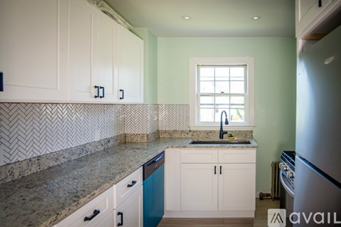 A kitchen with white cabinets and a marble countertop.