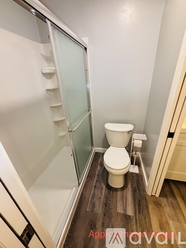 A toilet in a small bathroom with a glass shower door.