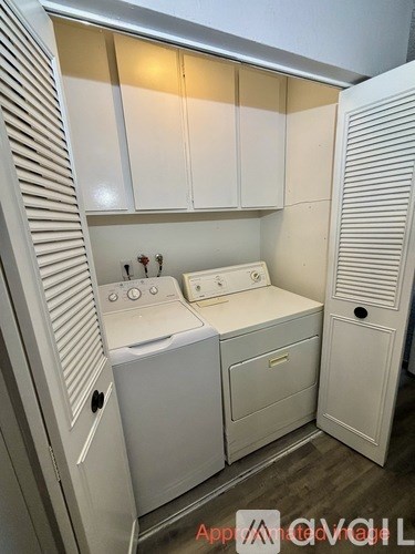A small, white, built-in kitchen with a washer and dryer.
