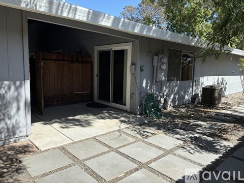 A patio area of a house with a white wall and a door.