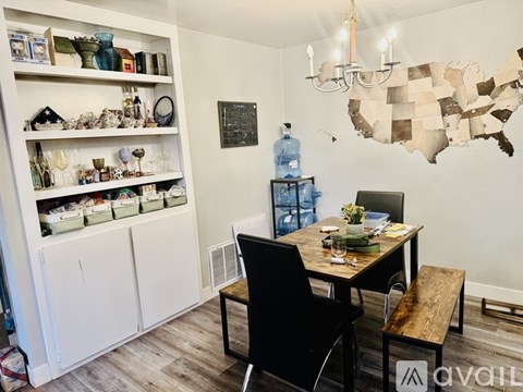 A dining room with a wooden table and chairs, a chandelier, and a map of the United States on the wall.