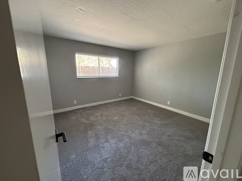A room with a carpeted floor and two doors, one of which is open.