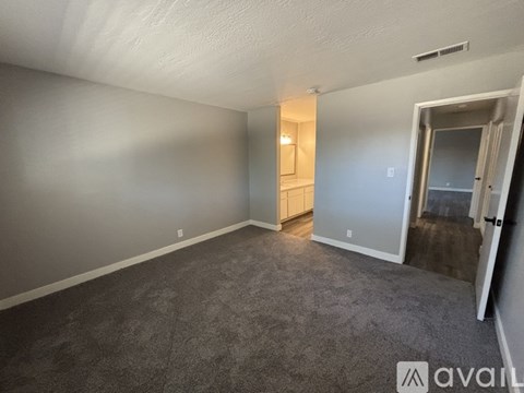 A carpeted room with a window covered by white curtains.