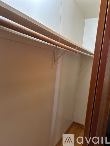 A white closet with a wooden rod.