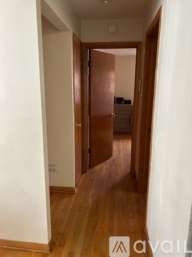 A hallway with wooden floors and white walls.