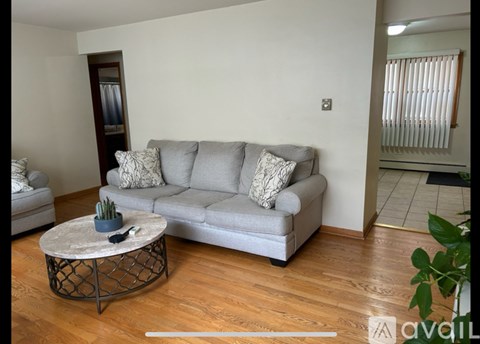 A living room with a grey couch and a round table with a plant on it.