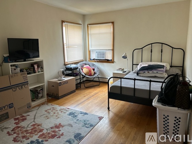 A bedroom with a bed, a chair, and boxes on the floor.