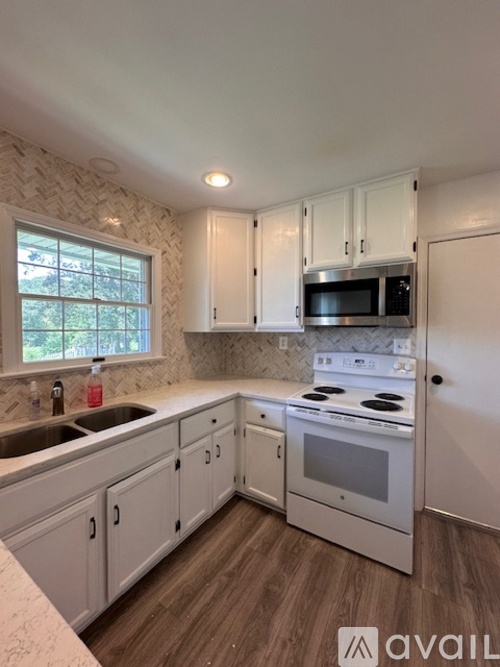 A kitchen with white cabinets and a wooden floor.