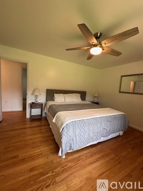 A bedroom with a bed, nightstand, and ceiling fan.