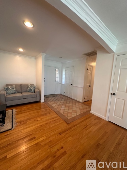 A living room with a grey couch and wooden floors.